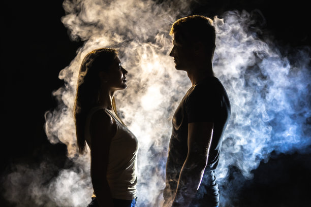 在黑暗的背景中，一对夫妇站在烟雾中图片下载