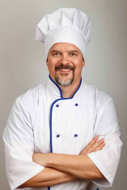 图为一名面带微笑的专业厨师身穿厨师制服，背景为灰色图片下载