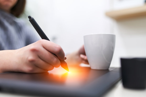 特写手的女性插画设计师，握笔和绘画在电脑图形板。自由的概念。图片下载