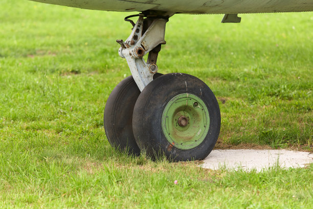 一架旧飞机的旧起落架在绿色草地的背景上的特写。图片下载