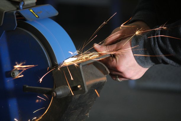 铁匠用带火花的磨石磨金属图片下载