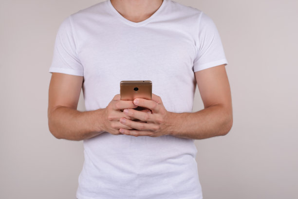 裁剪近距离观看工作室照片肖像满意的高兴的快乐的清凉的时尚帅气的强壮的男子气概的学生使用金色电话孤立的灰色背景图片下载