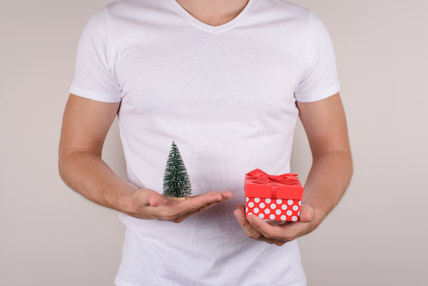 图像图片照片肖像特写快乐、兴奋、高兴、高兴的人抱着小玩具圣诞树和带丝带弓孤立的灰色背景盒子图片下载