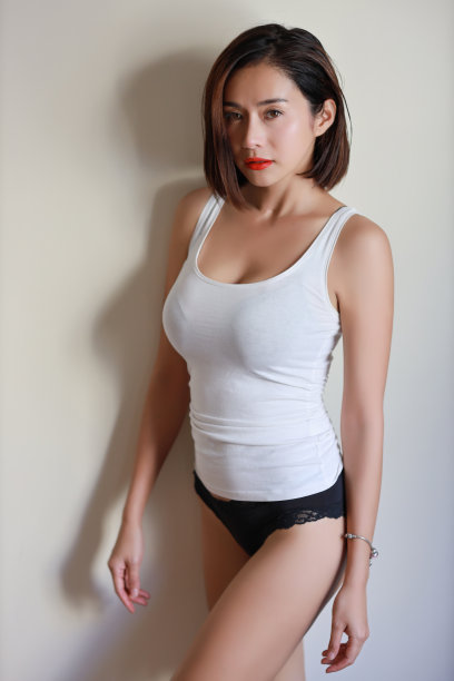 全长年轻的亚洲女性，红色的嘴唇和短发在白色的裙子与美丽的脸和看着相机在白色的墙壁图片下载