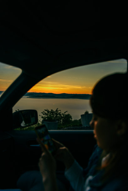 女人在车里用智能手机看日出的背景图片下载