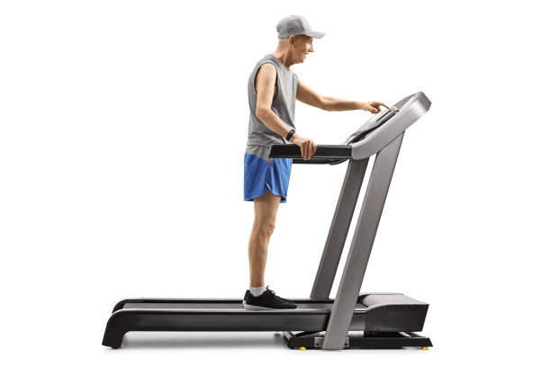 一位老人站在跑步机上，按下显示屏上的按钮图片下载