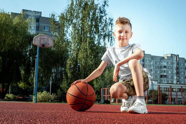一个在篮球场上拿着篮球的男孩的肖像。运动的概念生活方式，训练，运动，休闲，度假。图片下载