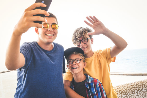 一群小男孩在学校外面自拍。时髦的快乐男孩享受新的趋势技术一起分享社交媒体上的照片和视频在线。青年科技团结和z世代概念。图片下载