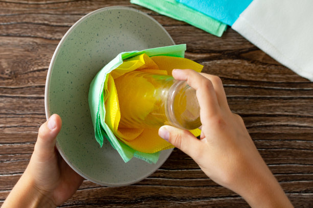 节日的餐桌布置。孩子从餐巾纸上加上一朵花。手工制作的。儿童创意项目，手工艺品，儿童工艺品。图片下载