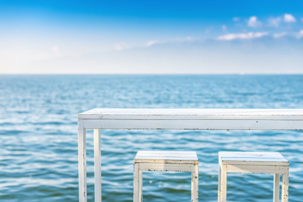 白色的桌子和椅子靠着蓝色的湖图片下载