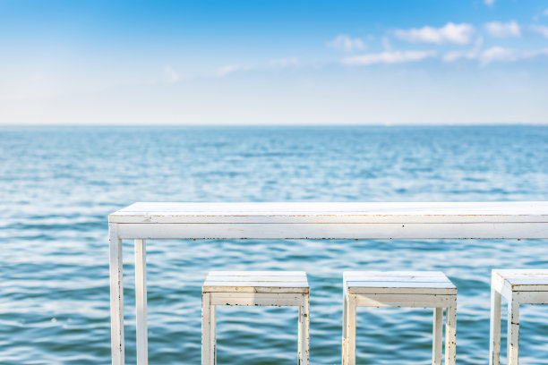 白色的桌子和椅子靠着蓝色的湖图片下载