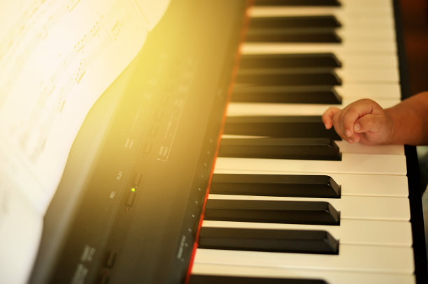 手小的儿子弹钢琴，孩子的钢琴键盘-形象图片下载