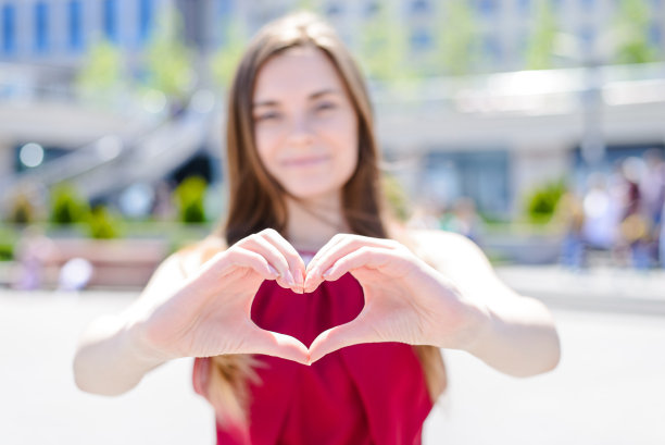 我爱你!送你我的心!年龄十几岁丈夫妻子男朋友喜欢关心梦幻的概念。裁剪近距离的照片肖像，漂亮开朗的无忧无虑的女孩显示心的自然城市背景图片下载