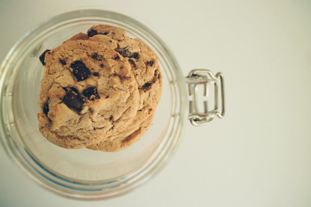 俯视图自制美味的巧克力片曲奇饼干在玻璃罐准备简单的早餐或咖啡与拷贝空间零食，选择性的焦点。复古的照片和电影风格。图片下载