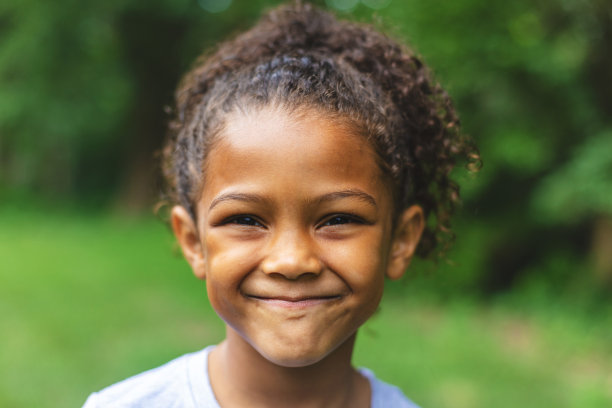6岁的非洲裔美国华裔女孩摆姿势肖像在郁郁葱葱的户外后院设置图片下载