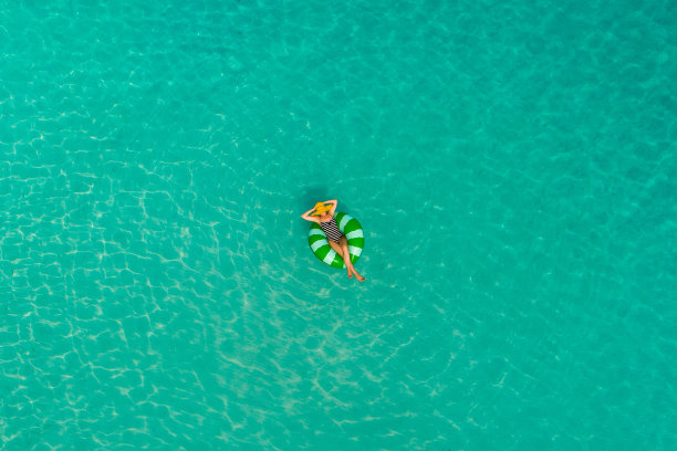 鸟瞰图，苗条的女人在透明的塞舌尔绿松石海游泳圈甜甜圈。夏日的海景带着少女，美丽的海浪，五颜六色的水。无人机俯视图图片下载