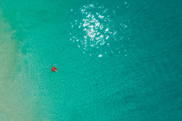 鸟瞰图，苗条的女人在透明的塞舌尔绿松石海游泳圈甜甜圈。夏日的海景带着少女，美丽的海浪，五颜六色的水。无人机俯视图图片下载