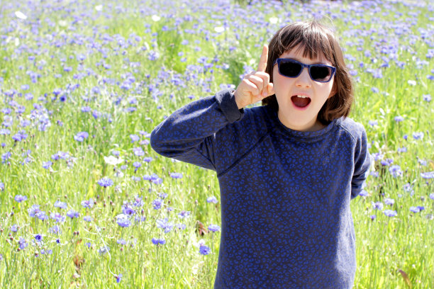 快乐的孩子与蓝色太阳镜表达灵感的惊喜，花卉户外图片下载
