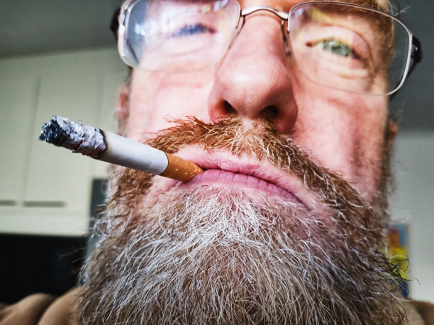 胡子男人抽烟，嘴里叼着烟图片下载