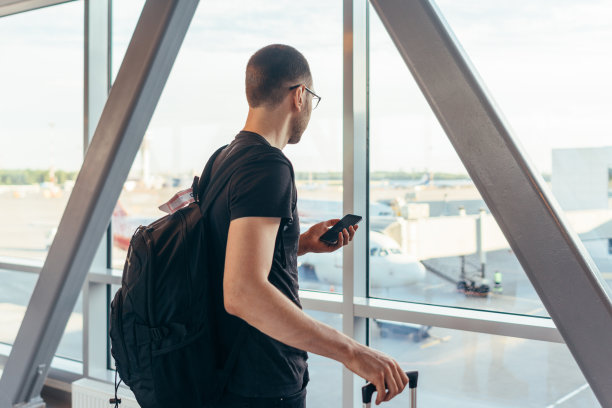 年轻女子站在机场窗口附近拿着手机图片下载