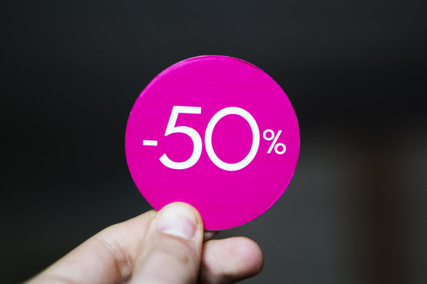 出售50%红色标签在手。折扣标签贴纸hold在手指背景。图片下载