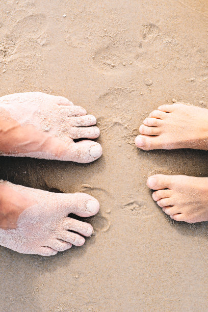 两双脚在金色的沙滩上。假期的概念。从上面的观点图片下载