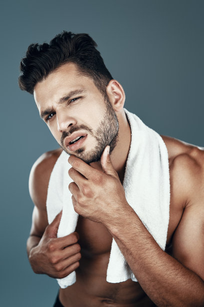 英俊年轻的赤膊男子看着相机，而站在灰色的背景图片下载