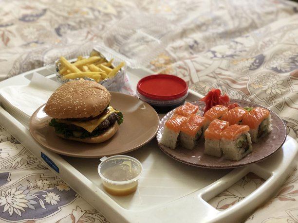 床上的食物托盘上放着汉堡和寿司图片下载