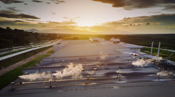 铜屋顶上的金属烟囱冒着烟，阴天傍晚的景观绿色植物和泰国工厂的砖窑和烟囱，概念环境。图片下载