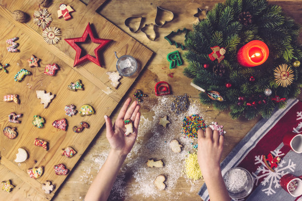 女性的手装饰圣诞饼干在木桌上图片下载