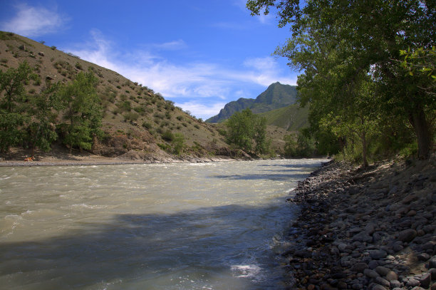 一条湍急的河流流经山脚下的山谷，流过岩石海岸。图片下载