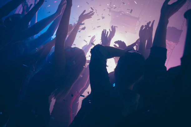 特写照片中很多人在夜总会跳舞，紫光、五彩纸屑、雾气缭绕，夜总会的人举起手，正装打扮图片下载