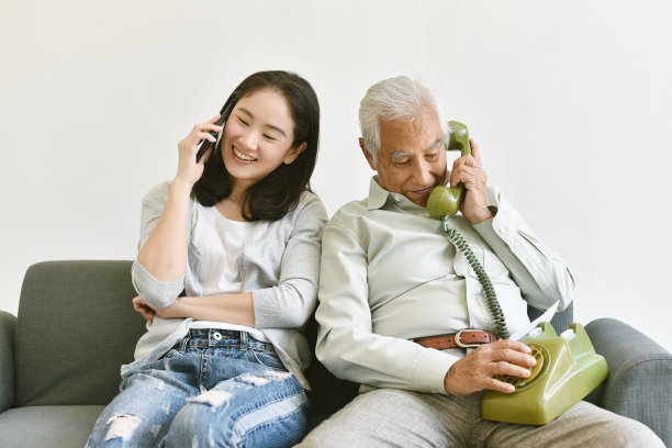 幸福的家庭关系，亚洲老父亲和微笑的女儿互相打电话，交流在不同的技术世代，智能手机和电话。图片下载