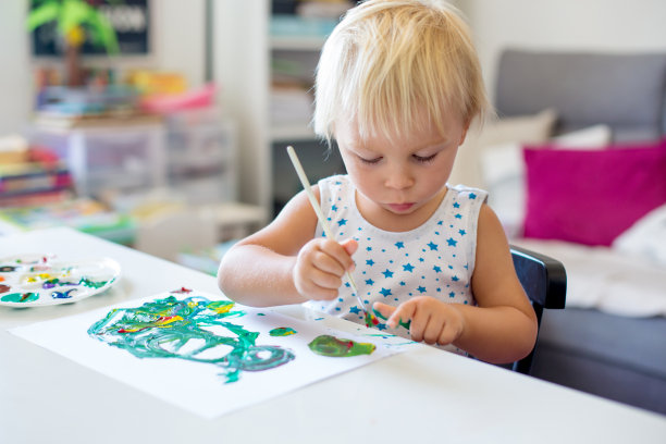 蹒跚学步的小男孩，在家画画，学习动作协调素材图片