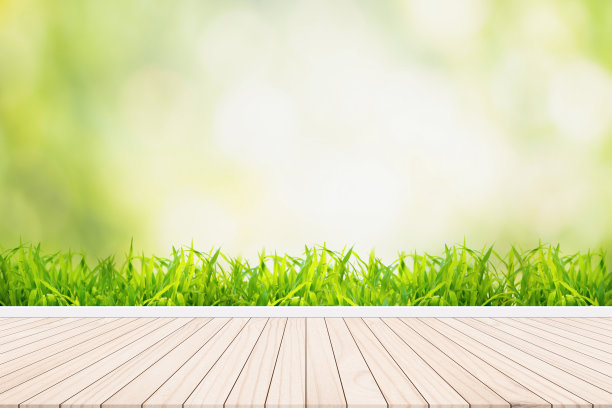 木地板以清新的草为背景，以虚化的自然为背景图片下载