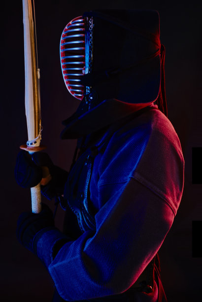 近景，剑道战士穿着盔甲，传统和服，头盔练习武术与shinai竹剑，黑色背景图片下载