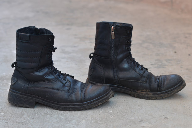 一双结实的旧皮靴，灰色背景，旧鞋图片下载