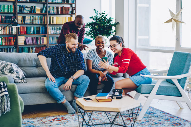 一群欢快的多种族朋友在手机上观看社交网络上的搞笑视频，微笑的男女潮人在家里一起看智能手机上的搞笑照片图片下载
