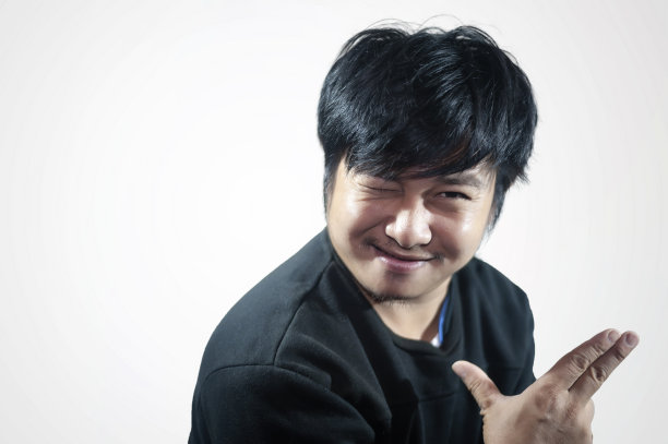 年轻人闭着眼睛，用手势站在灰色的背景上。图片下载