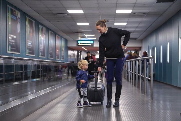 一位年轻的母亲和她蹒跚学步的孩子探索机场航站楼。图片下载