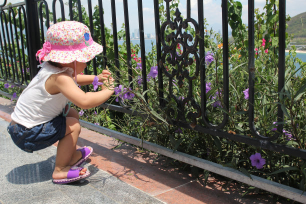 一个小女孩正在公园里看和闻紫色的花图片下载