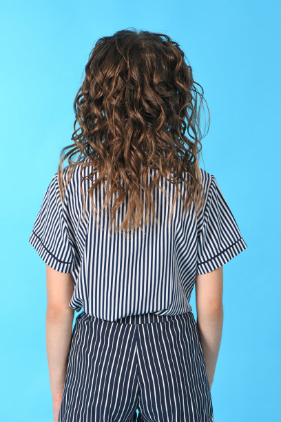 后视图的女孩与卷发。孤立在蓝色背景。图片下载