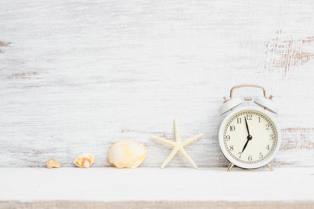 白色闹钟与海星，海贝在白色生锈的木头背景。背景概念暑假度假时间，海滩旅游度假时间。图片下载