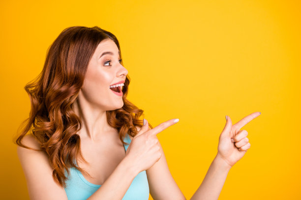 照片的狐狸姜时尚可爱的漂亮迷人的甜美迷人的女朋友指着某处穿着蓝绿色背心，而孤立在黄色明亮的颜色背景图片下载