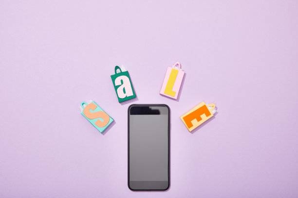 俯视图智能手机附近的彩色玩具购物袋与销售字母在紫罗兰图片下载