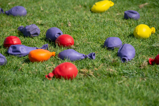 在夏天的绿草地上玩气球游戏。五颜六色的气球装满了草地上的沙子。图片下载