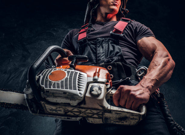 低角度的照片，一个伐木工人与链锯在一个黑暗的工作室图片下载