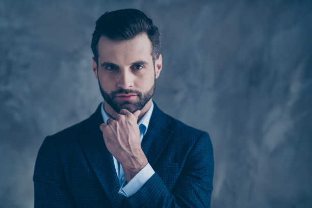肖像迷人的男子触摸他的下巴看起来穿着时尚的夹克孤立在灰色的背景图片下载