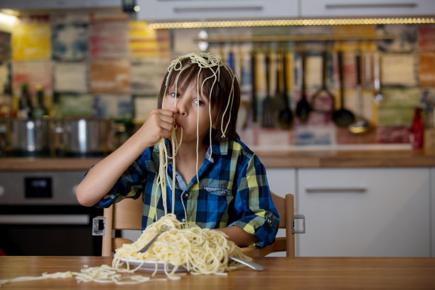 学龄前的小男孩，可爱的孩子，午餐吃意大利面，弄得一团糟图片下载
