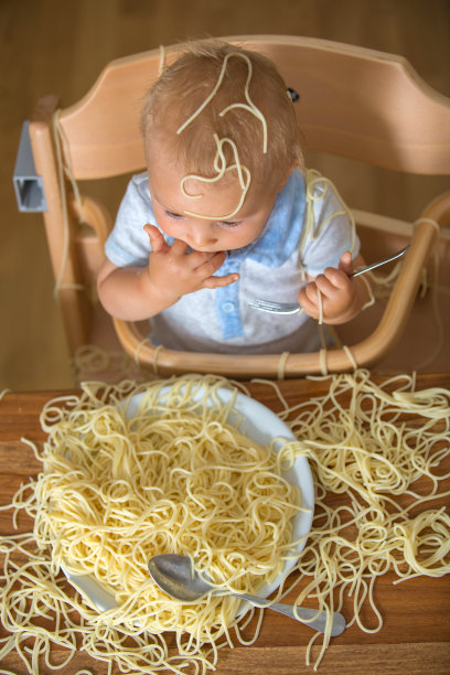 小男孩，蹒跚学步的孩子，午餐吃意大利面，弄得一团糟图片下载